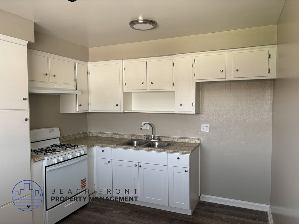 A kitchen with white cabinets and a stove top oven.